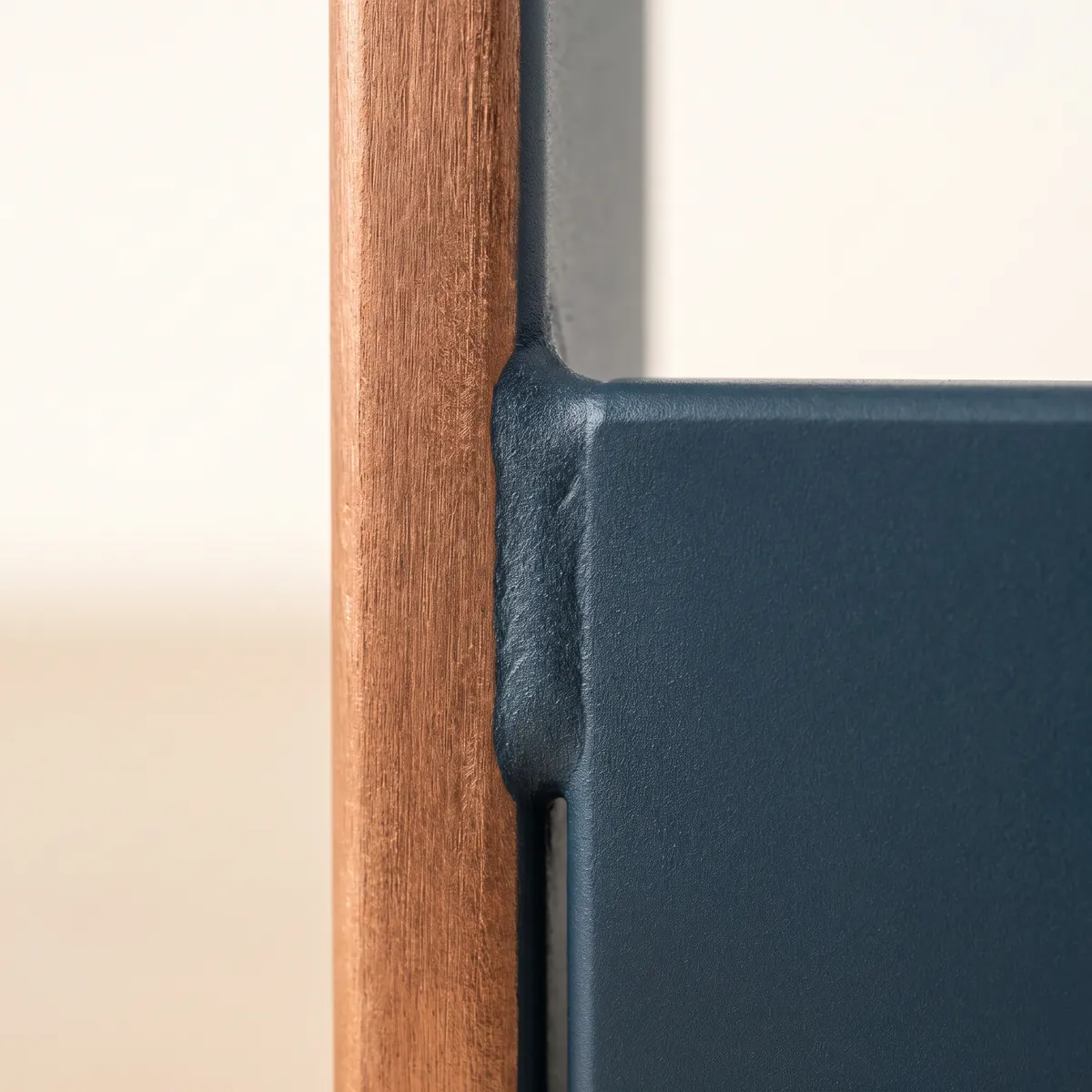 A brushed copper bar joined to a mineral-blue steel plate, with the seam in focus.